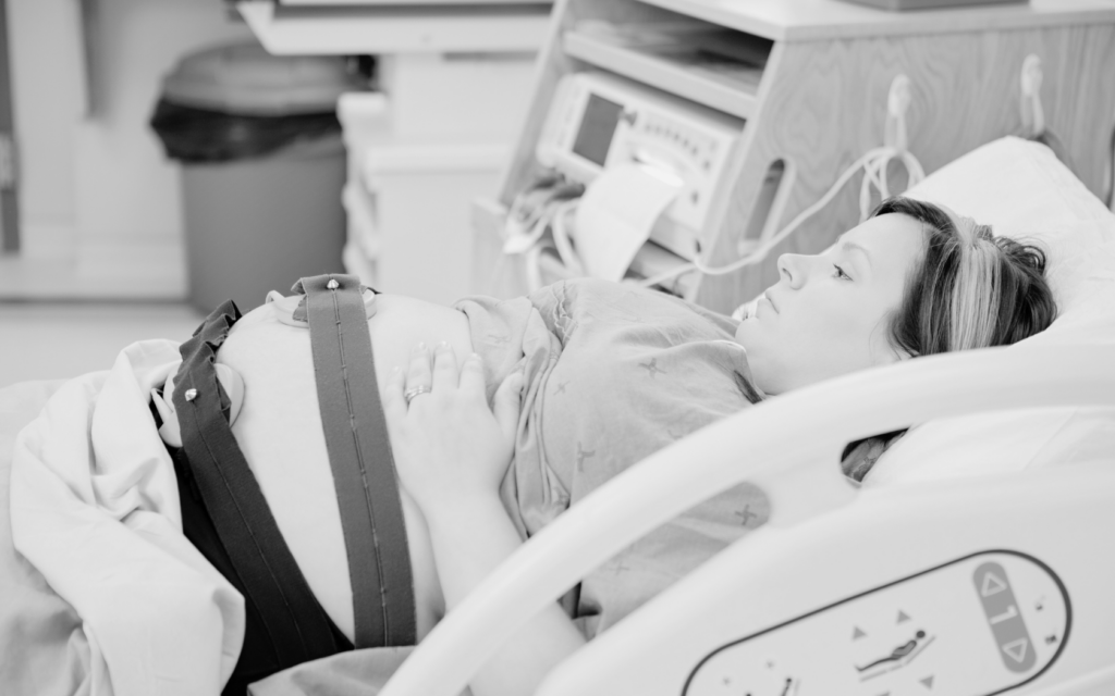 A woman in labor lying in a hospital bed with monitoring equipment.